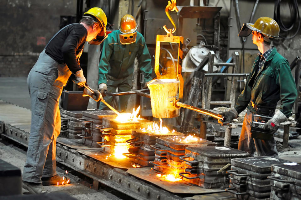 Three men working in a steel mill with molten steel being poured
