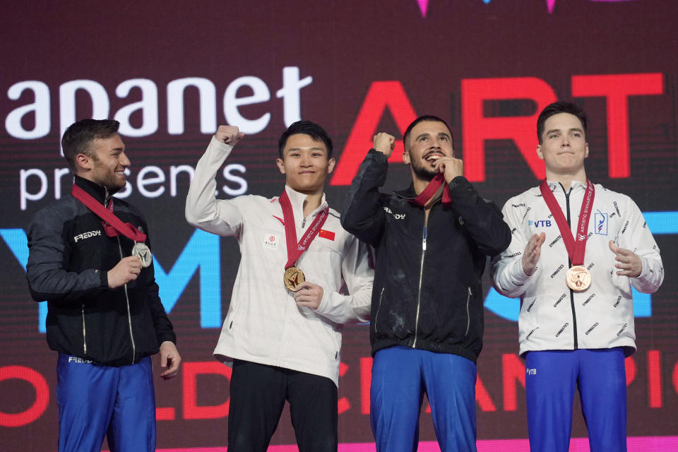 Lan Xingyu, center left, of China, with his gold medal, Marco Lodadio, left, of Italy, with his silver medal, and two bronze medalists, Salvatore Maresca, center right, of Italy, and Grigorii Klimentev, of the Russian Gymnastics Federation, pose for photos and video during the victory ceremony for the men's rings final in the FIG Artistic Gymnastics World Championships in Kitakyushu, western Japan, Saturday, Oct. 23, 2021. (AP Photo/Hiro Komae)