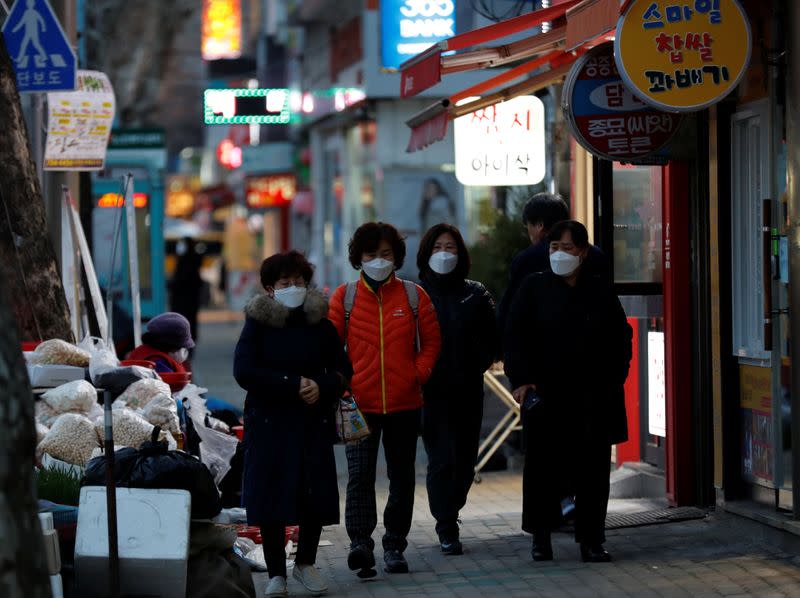 Women wearing protective masks after the rapid rise in confirmed cases of the novel coronavirus disease of COVID-19 make their way at a market street in Daegu