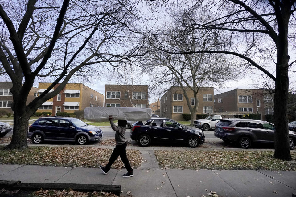 Nehemiah Powell, 14, carries a mattress Saturday, Nov. 21, 2020, for his brother's new bed to a storage space outside his family's apartment in Skokie, Ill., as his family prepares to move to Georgia where living costs are lower. (AP Photo/Charles Rex Arbogast)