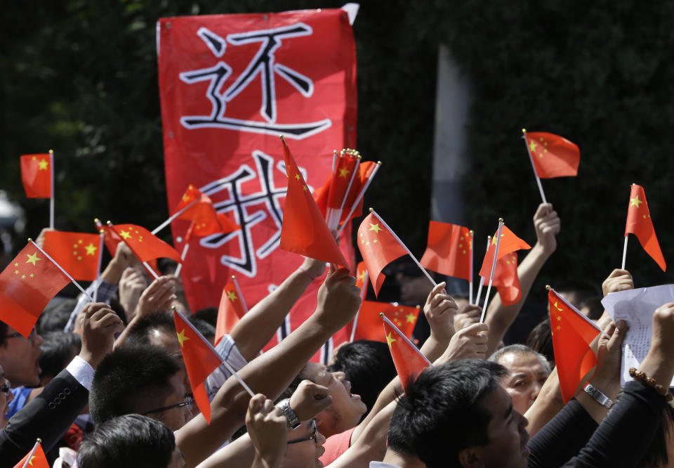 Chinese protesters march with a banner which reads "Return My Mountains" outside the Japanese embassy in Beijing, China, Wednesday, Sept. 12, 2012. A territorial flare-up between China and Japan intensified as two Beijing-sent patrol ships arrived near disputed East China Sea islands in a show of anger over Tokyo's purchase of the largely barren outcroppings from their private owners. (AP Photo/Ng Han Guan)