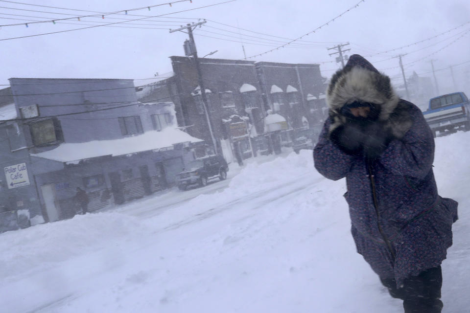 In this Feb. 23, 2019, photo, a woman shields her face from the wind during a snow storm as she walks on Front Street in Nome, Alaska. (AP Photo/Wong Maye-E)