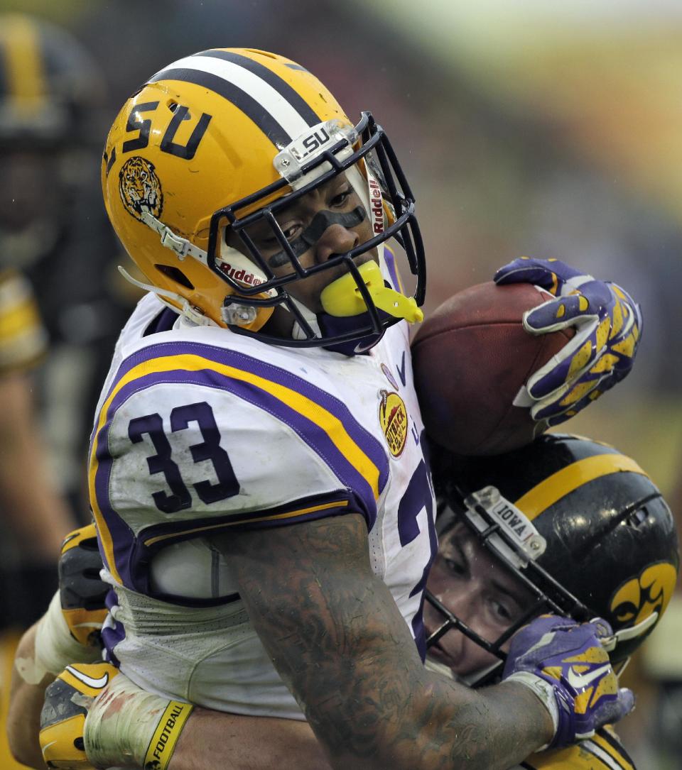 LSU running back Jeremy Hill (33) carries Iowa linebacker James Morris (44) into the end zone to score on a 14-yard touchdown run during the second quarter of the Outback Bowl NCAA college football game Wednesday, Jan. 1, 2014, in Tampa, Fla. (AP Photo/Chris O'Meara)