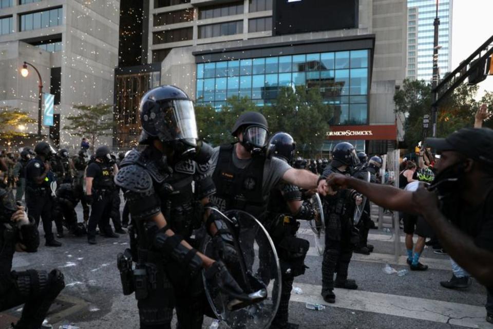 Un agente y un manifestante chocan sus puños en medio de un enfrentamiento policial durante una protesta celebrada en Atlanta el 1 de junio. (Foto: Dustin Chambers / Reuters).