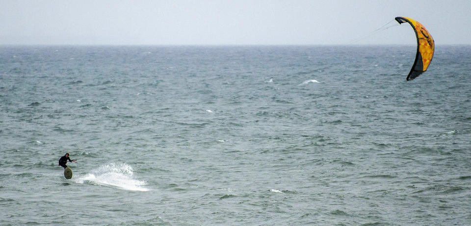 A kitesurfer took advantage of the high winds to ride the waves just north of the Huntington Beach Pier Rain in Huntington Beach on Thursday, Jan. 17, 2019, as another storm brought more rain Orange County and Southern California. (Mark Rightmire/Orange County Register via AP)