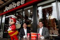 Ernesto Tanmantiong, the president and CEO of Philippine national champion Jollibee Foods Corp, and Ysmael Baysa, its CFO, pose for a picture outside a Jollibee branch in Pasig City,