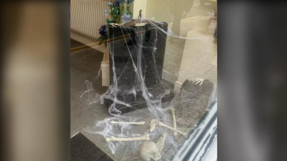 假蜘蛛網、骷髏旁放置一塊真墓碑。（圖／翻攝自《每日郵報》）
