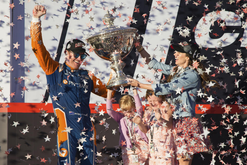 FILE - In this Sept. 16, 2018, file photo, Scott Dixon holds the Indy Car Championship trophy with his wife Emma Davies and their children Poppy and Tilly Davies Dixon, in Sonoma, Calif. IndyCar is ready to go racing again after six long months spent working on the business side of the series. Deals done since Scott Dixon wrapped up his fifth IndyCar championship last September include new title sponsorship from Japanese communications giant NTT. (AP Photo/Elijah Nouvelage, File)