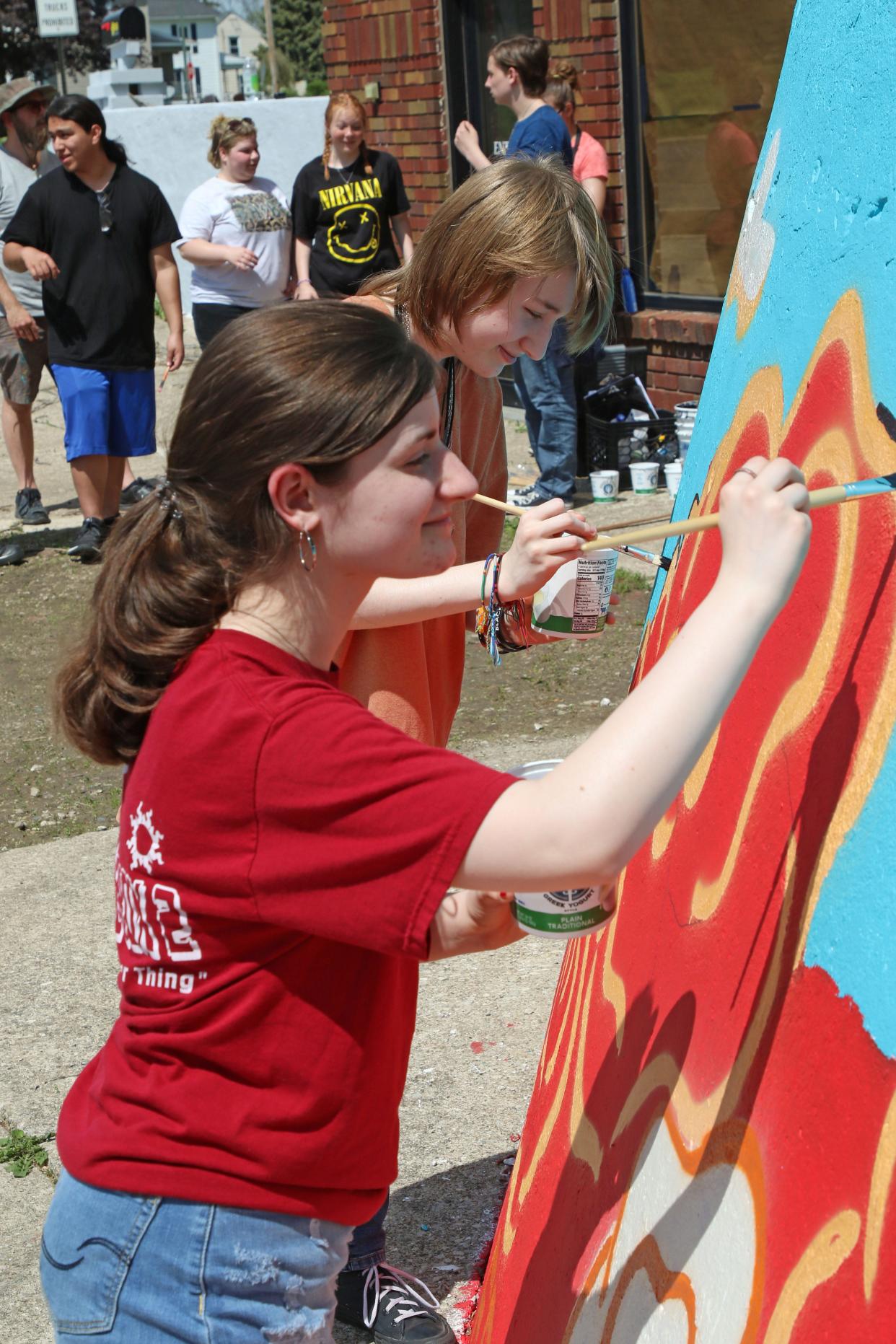 Fremont Ross High School students Brianna Boskovich, front, and Connor White put the finnishing touches on an Ohio-themed mural at the corner of North Front Street and North Street. Members of Ross' Art Club created the mural for the building, recently purchased by Wynn-Reeth/RSS, across from the fairgrounds.