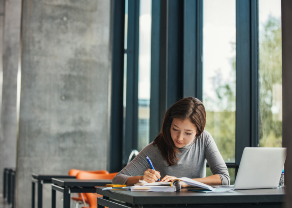 A student taking notes in a library.