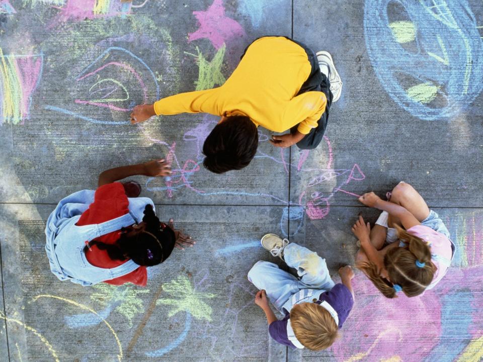 Children drawing with chalk on pavement.