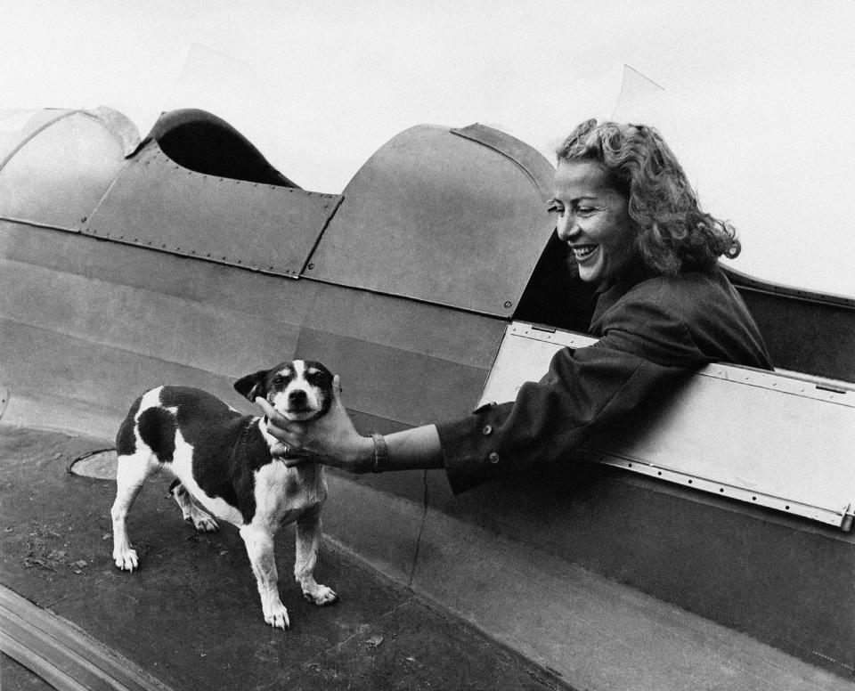 Romanian aviatrix Irina Burnaia, onboard of an airplane, is caressing her little good luck dog before starting her flight circa 1930.