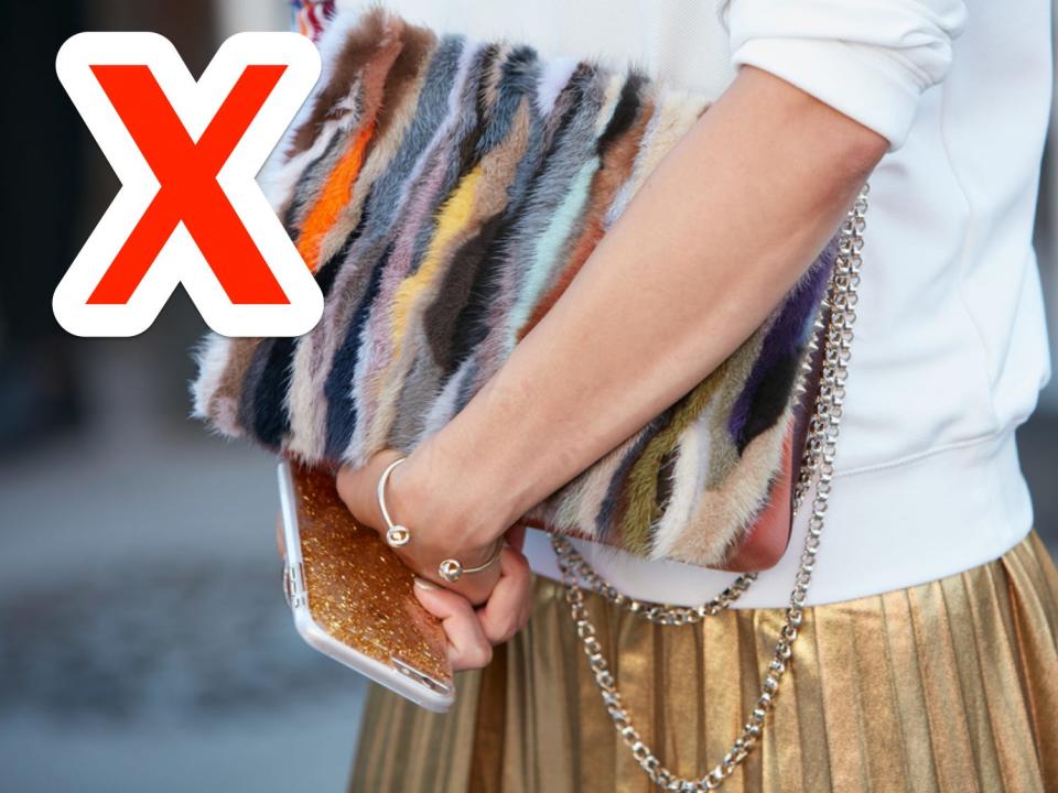 red x over a woman holding a multicolored faux fur purse and wearing a white sweatshirt over a gold pleated skirt