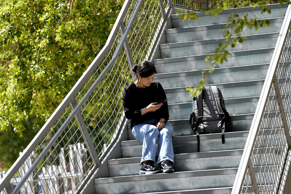 Fahima Sultani checks her phone on campus at Arizona State University, Friday, April 7, 2023, in Tempe, Ariz. Sultani and others tried for days in the summer of 2021 to get into the Kabul airport, only to be turned away by the gun-wielding extremists as the Taliban swept back into power. After a harrowing escape, Sultani is one of more than 60 Afghan women who arrived at ASU in December 2021. (AP Photo/Matt York)