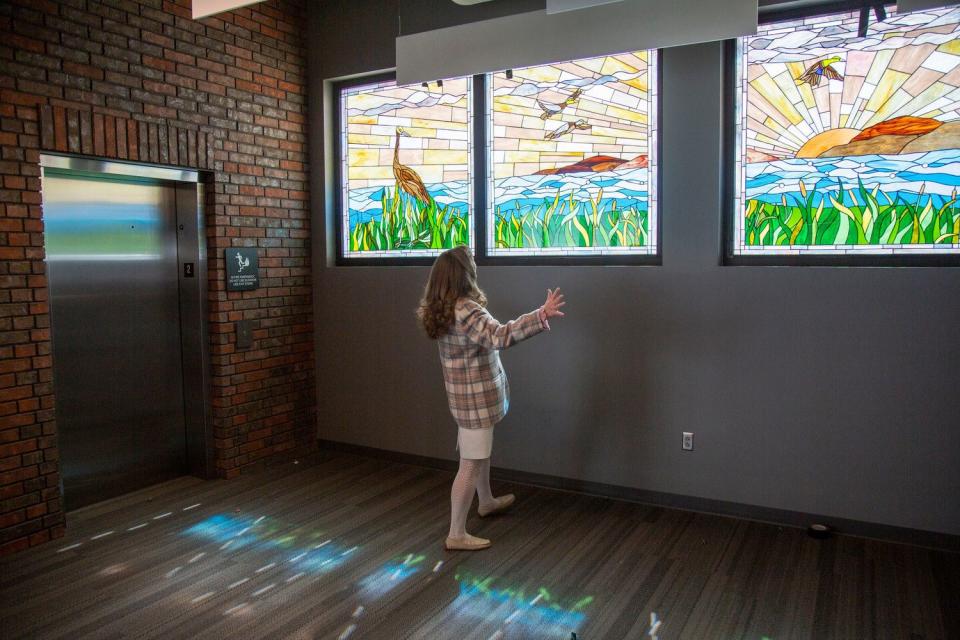 Provo artist Jeanne Gomm stands in front of her Utah Lake stained-glass mural at the unveiling of her artwork at Provo Airport on April 5.