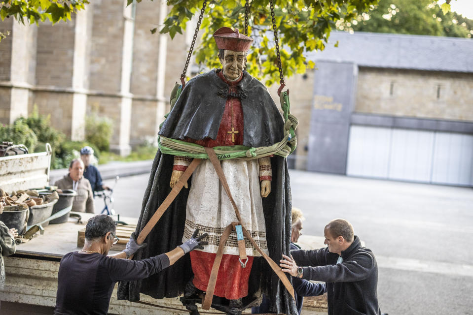 The sculpture of Cardinal Franz Hengsbach is loaded onto the back of a truck by a crane in front of Essen Cathedral in Essen, Germany, Monday Sept. 25, 2023. A statue of late German Cardinal Franz Hengsbach was removed from outside a cathedral in western Germany after allegations of sexual abuse against him surfaced. (Christoph Reichwein/dpa via AP)