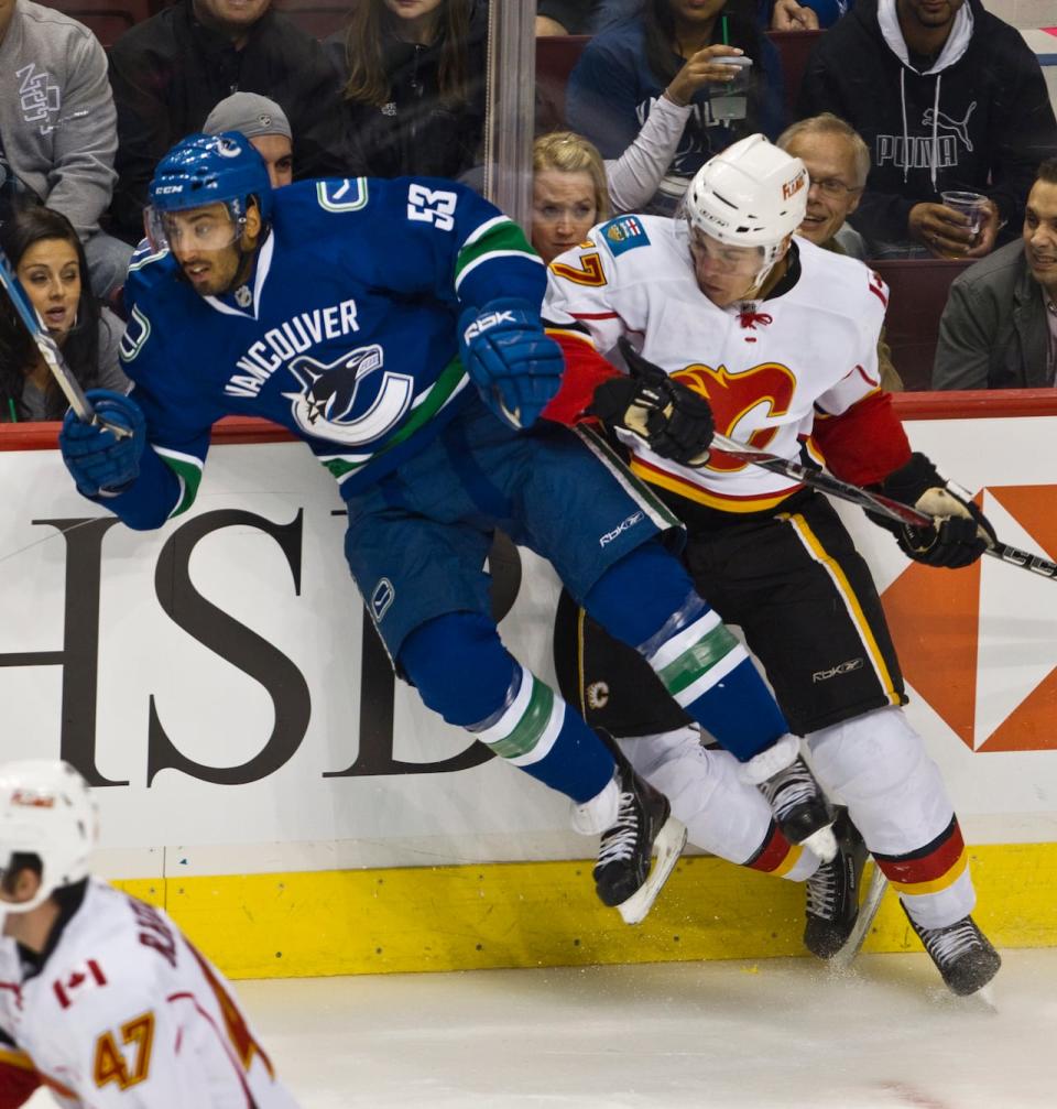 Prab Rai, left, seen here in a 2010 NHL pre-season game with the Vancouver Canucks, has been charged with fraud, say Surrey RCMP. (Andy Clark/Reuters - image credit)