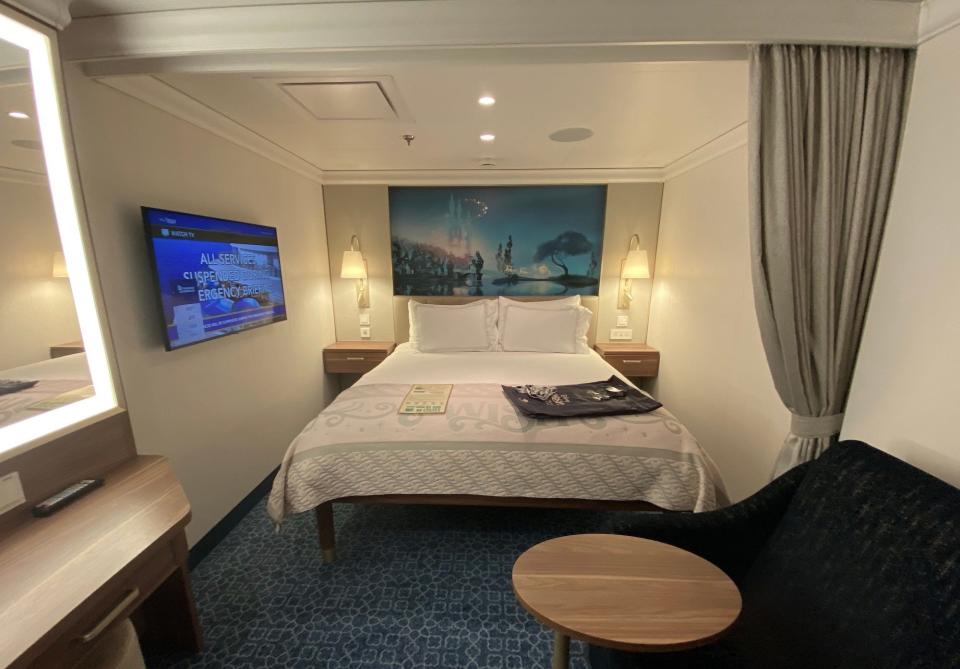 The bed area of a standard stateroom aboard the Disney Wish cruise.