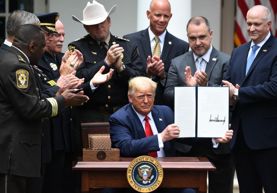 Surrounded by law enforcement officials, President Donald Trump shows his signature on an executive order on Safe Policing for Safe Communities in the Rose Garden of the White House On Tuesday. (Photo: SAUL LOEB via Getty Images)