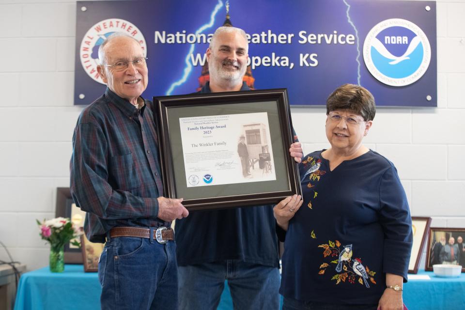 Alan Winkler, left, holds his National Weather Service Family Heritage Award with his wife, Effa, right, and Shawn Byrne, observing program leader for the Topeka station, during an event last week at the Topeka station.