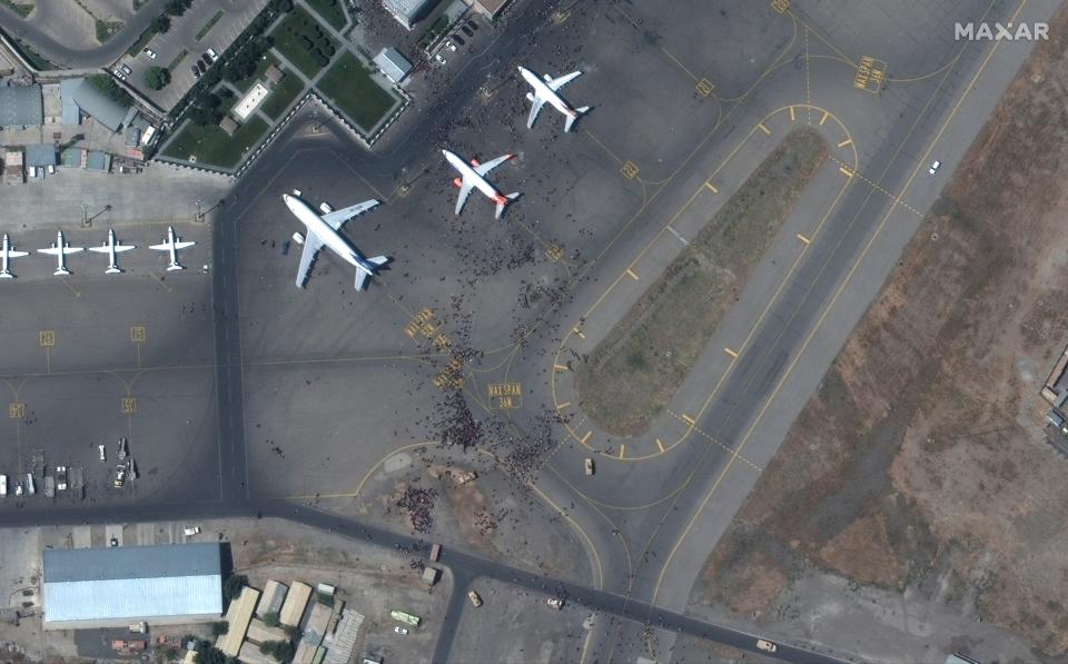 This satellite photo from Maxar Technologies shows swarms of people on the tarmac at Kabul International Airport, also known as Hamid Karzai International Airport, Monday Aug. 16, 2021. Afghans rushed onto the tarmac of the capital's airport on Monday as thousands tried to flee the country after the Taliban seized power with stunning speed. Some clung to the side of a U.S. military transport plane before takeoff, in a widely shared video that captured the sense of desperation as America's 20-year war comes to a chaotic end. (Satellite image ©2021 Maxar Technologies via AP)