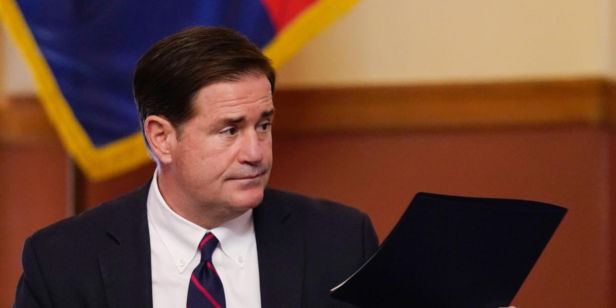 In this Nov. 30, 2020 file photo, Arizona Gov. Doug Ducey hands over his signed election documents to certify the election results for federal, statewide, and legislative offices and statewide ballot measures at the official canvass at the Arizona Capitol in Phoenix