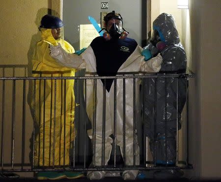 A worker in a hazardous material suit is helped to undress after coming out of an apartment unit where a man diagnosed with the Ebola virus was staying in Dallas, Texas, October 5, 2014. REUTERS/Jim Young