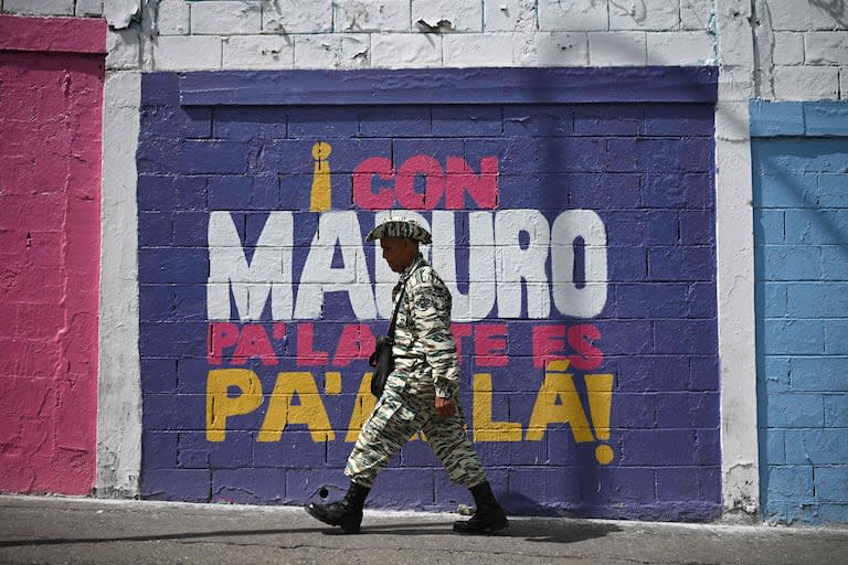 Un miembro de la milicia bolivariana pasa junto a un mural de campaña del presidente venezolano y candidato presidencial Nicolás Maduro en Caracas el 24 de julio de 2024, antes de las elecciones presidenciales del domingo.