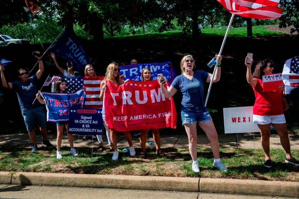 Supporters of US President Donald Trump stand with signs and flags as his motorcade leaves his golf club, Trump National, in Sterling, Virginia (Agence France-Presse/AFP via Get)