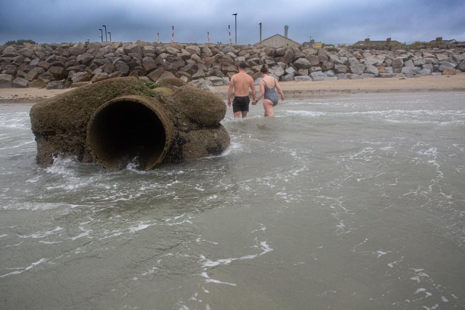 Water Outflow Pipe with tourist at Longrock beach between Penzance and Marazion in Cornwall , United Kingdom.