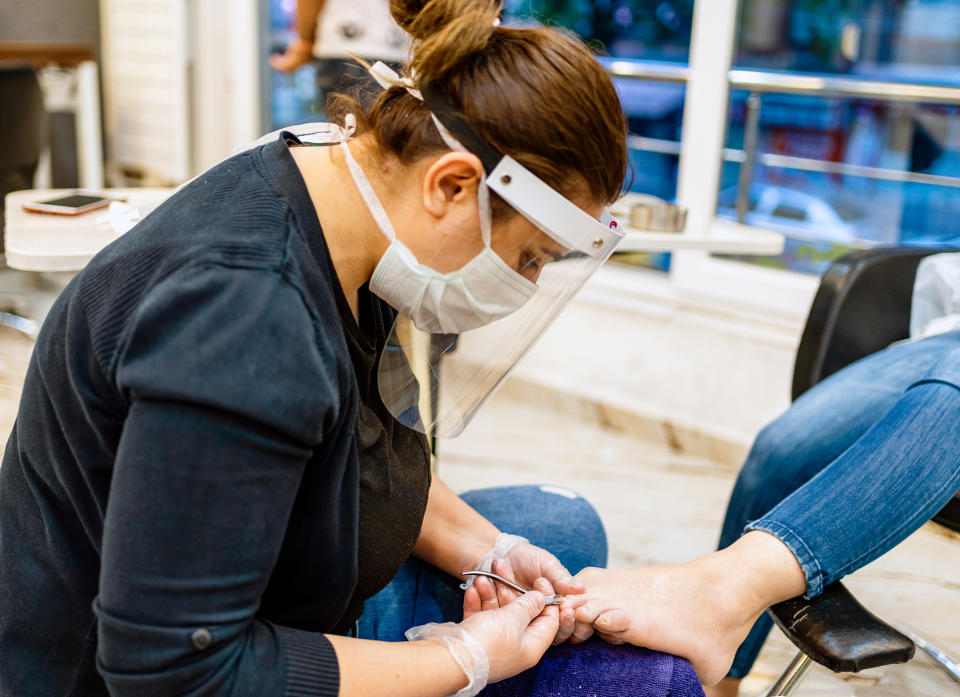 Woman with protective face mask on manicure treatment in beauty salon (Getty Images)