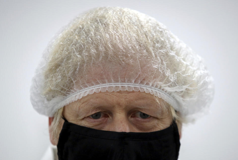 Britain's Prime Minister Boris Johnson wears protecting clothing as he visits SureScreen Diagnostics, amidst the coronavirus disease outbreak, in Derby, England, Monday Feb. 8, 2021. The British government has announced that manufacturer SureScreen Diagnostics has contracted to supply 20 million rapid lateral flow antigen tests, ensuring supply for UK over the coming months. (Phil Noble/Pool via AP)