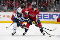 Washington Capitals center Lars Eller, right, tries to clear a puck from in front of the goal as he is pressured by Winnipeg Jets center Mark Scheifele in the first period of an NHL hockey game, Tuesday, Jan. 18, 2022, in Washington. (AP Photo/Patrick Semansky)