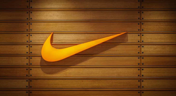 The swoosh logo for Nike Inc (NKE) is displayed on a wall made of wood panels.