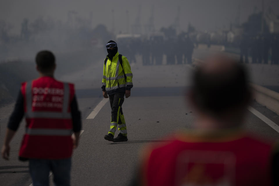 An oil worker stands in front of French police officers as he and others block the access to an oil depot in Fos-sur-Mer, southern France, Tuesday, March 21, 2023. The bill pushed through by President Emmanuel Macron without lawmakers' approval still faces a review by the Constitutional Council before it can be signed into law. Meanwhile, oil shipments in the country were disrupted amid strikes at several refineries in western and southern France. (AP Photo/Daniel Cole)