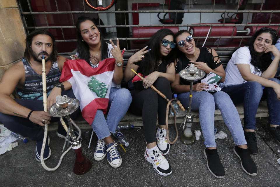 Anti-government protesters smoke water pipes during a protest in Beirut, Lebanon, Sunday, Oct. 20, 2019. Tens of thousands of Lebanese protesters of all ages gathered Sunday in major cities and towns nationwide, with each hour bringing hundreds more people to the streets for the largest anti-government protests yet in four days of demonstrations. (AP Photo/Hassan Ammar)