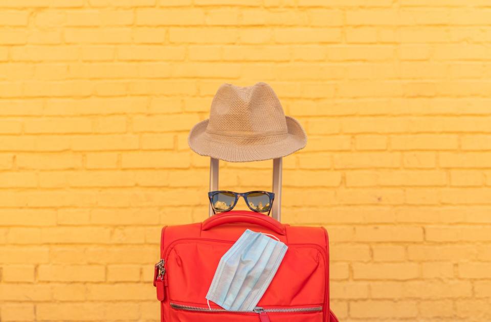 An image of a suitcase with a mask, sunglasses, and hat on it.