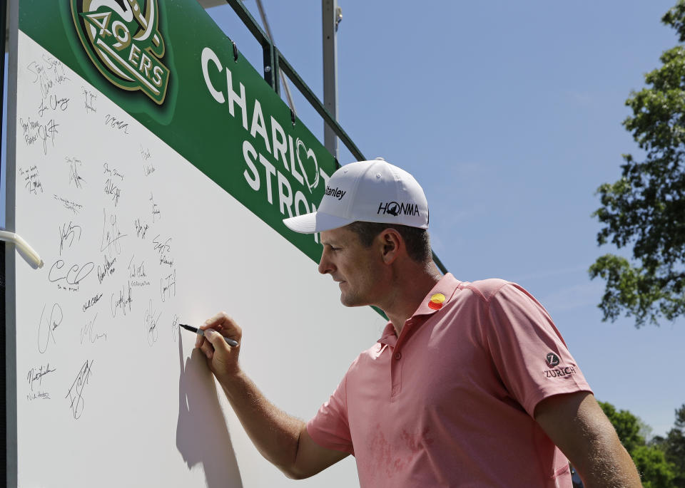 Justin Rose, of England, signs a board on the first tee in support of the victims of the shooting at the University of North Carolina-Charlotte during the first round of the Wells Fargo Championship golf tournament at Quail Hollow Club in Charlotte, N.C., Thursday, May 2, 2019. (AP Photo/Chuck Burton)