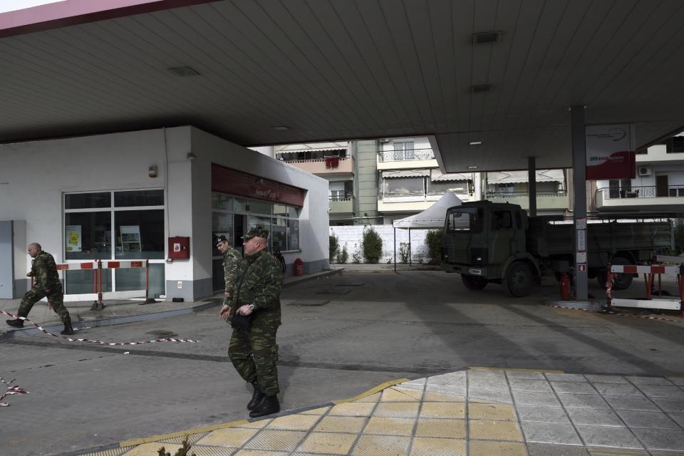 Military officers leave a gas station in the northern Greek city of Thessaloniki, on Thursday, Feb. 9, 2016 where an unexploded World War II bomb was found 5 meters (over 16 feet) deep. Authorities in Greece's second-largest city on Sunday are planning to evacuate up to 60,000 residents from their homes so experts can safely dispose of the unexploded World War II bomb. (AP Photo/Giannis Papanikos)