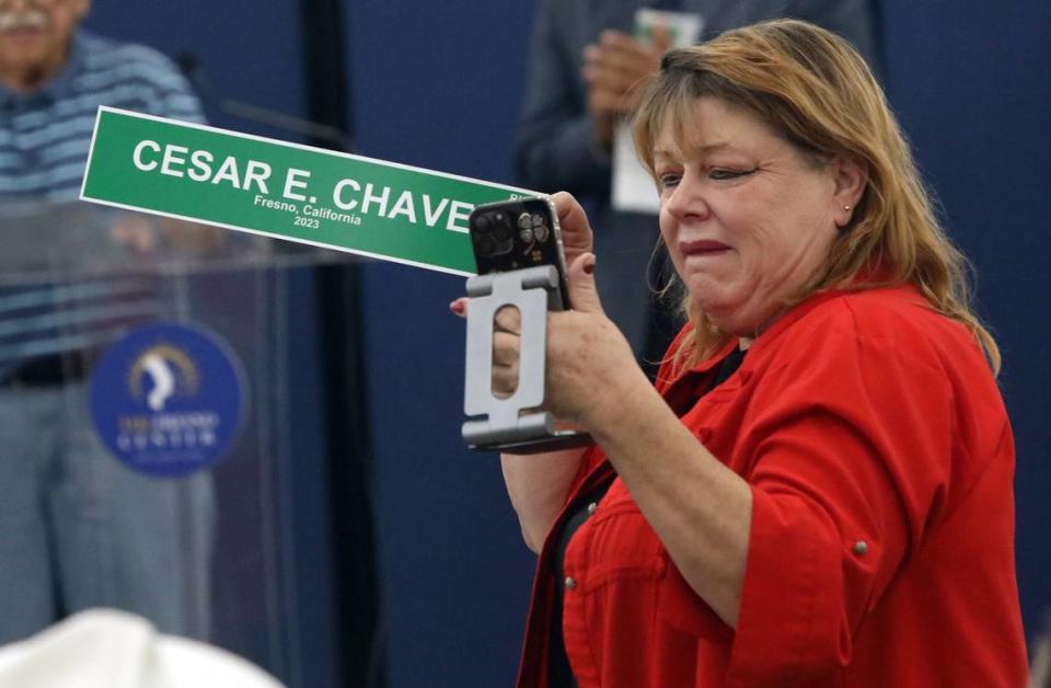 A woman holds up a copy of the Cesar Chavez Boulevard street sign during a July 26, 2024 celebration in southeast Fresno.