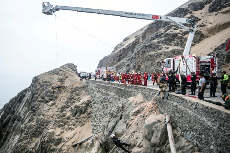 Rescuers, police and firefighters work at the scene after a bus plunged over a cliff when it collided with a truck on a coastal highway in Peru; the death toll now stands at 50