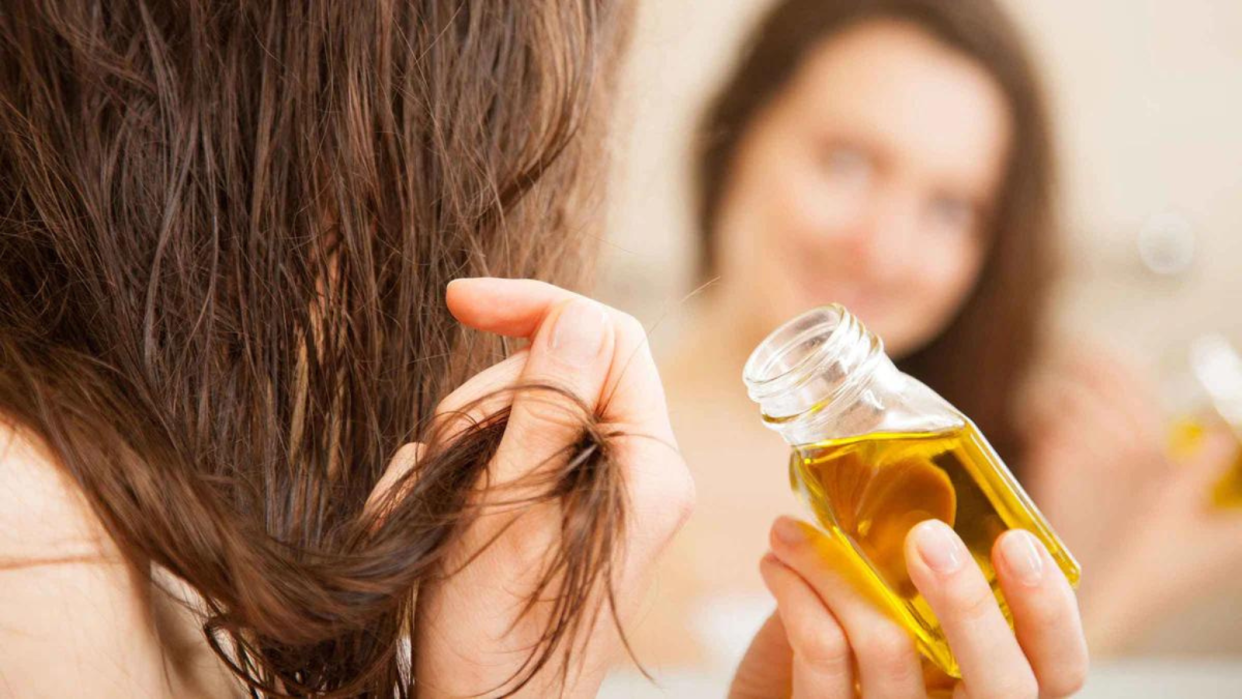  Woman putting hair oil on. 