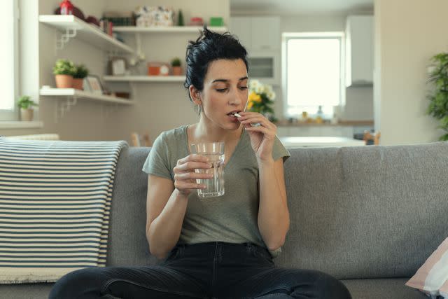 <p>PixelsEffect / Getty Images</p> Female taking tablet with glass of fresh water