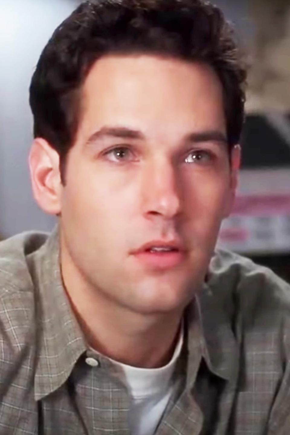 Paul Rudd in a plaid shirt, looking off-camera with a thoughtful expression