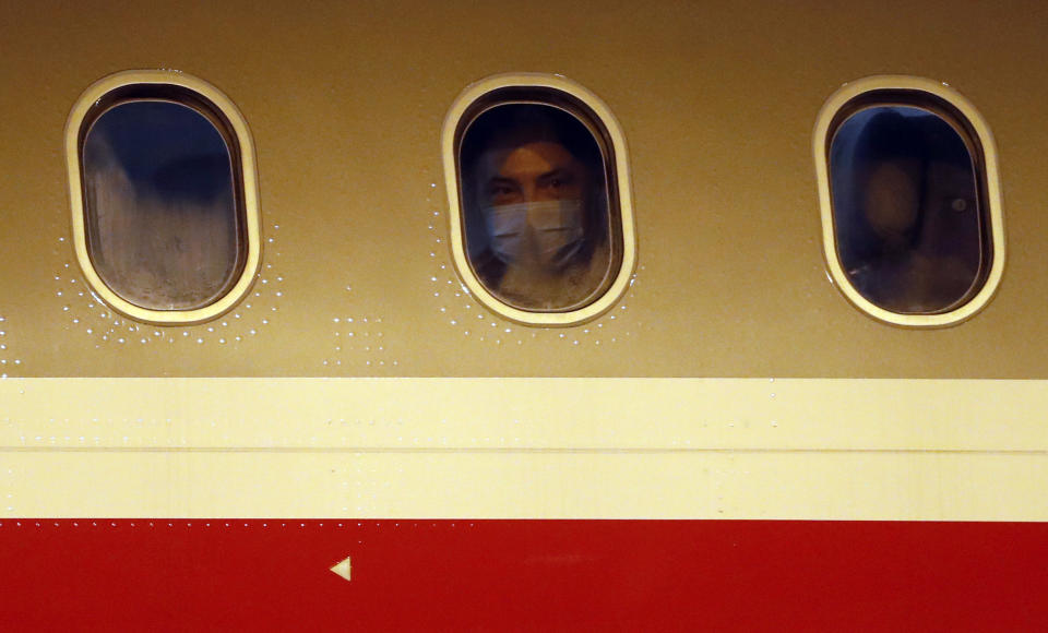 A man is seen in a window as Czech diplomats and their families arrive at the Vaclav Havel airport in Prague, Czech Republic, Monday, April 19, 2021. Russia has ordered 20 Czech diplomats to leave the country within a day in response to Prague's expulsion of 18 Russian diplomats. The Czech government has alleged the Russian Embassy staffers were spies for a military intelligence agency that was involved in a fatal ammunition depot explosion in 2014. (AP Photo/Petr David Josek)