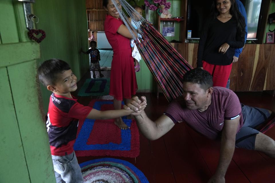 Jose Alves de Morais and his nephew Felipe embrace at a home, in Lago Serrado community, near Carauari, Brazil, Thursday, Sept. 1, 2022. A Brazilian non-profit created a model for land ownership that welcomes both local people and scientists to collaborate in preserving the Amazon. "This is something that doesn't exist here in the Amazon, it doesn't exist anywhere in Brazil. If it works, which it will, it will attract a lot of people's attention," Morais, a resident, told The Associated Press. (AP Photo/Jorge Saenz)