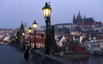 A woman with a covered face walks across the near empty Charles Bridge in Prague, Czech Republic, Thursday, April 2, 2020. The Czech Republic's government has approved further dramatic measures to try and stem the spread of the novel coronavirus called COVID-19. The coronavirus causes mild or moderate symptoms for most people, but for some, especially older adults and people with existing health problems, it can cause more severe illness or death. (AP Photo/Petr David Josek)