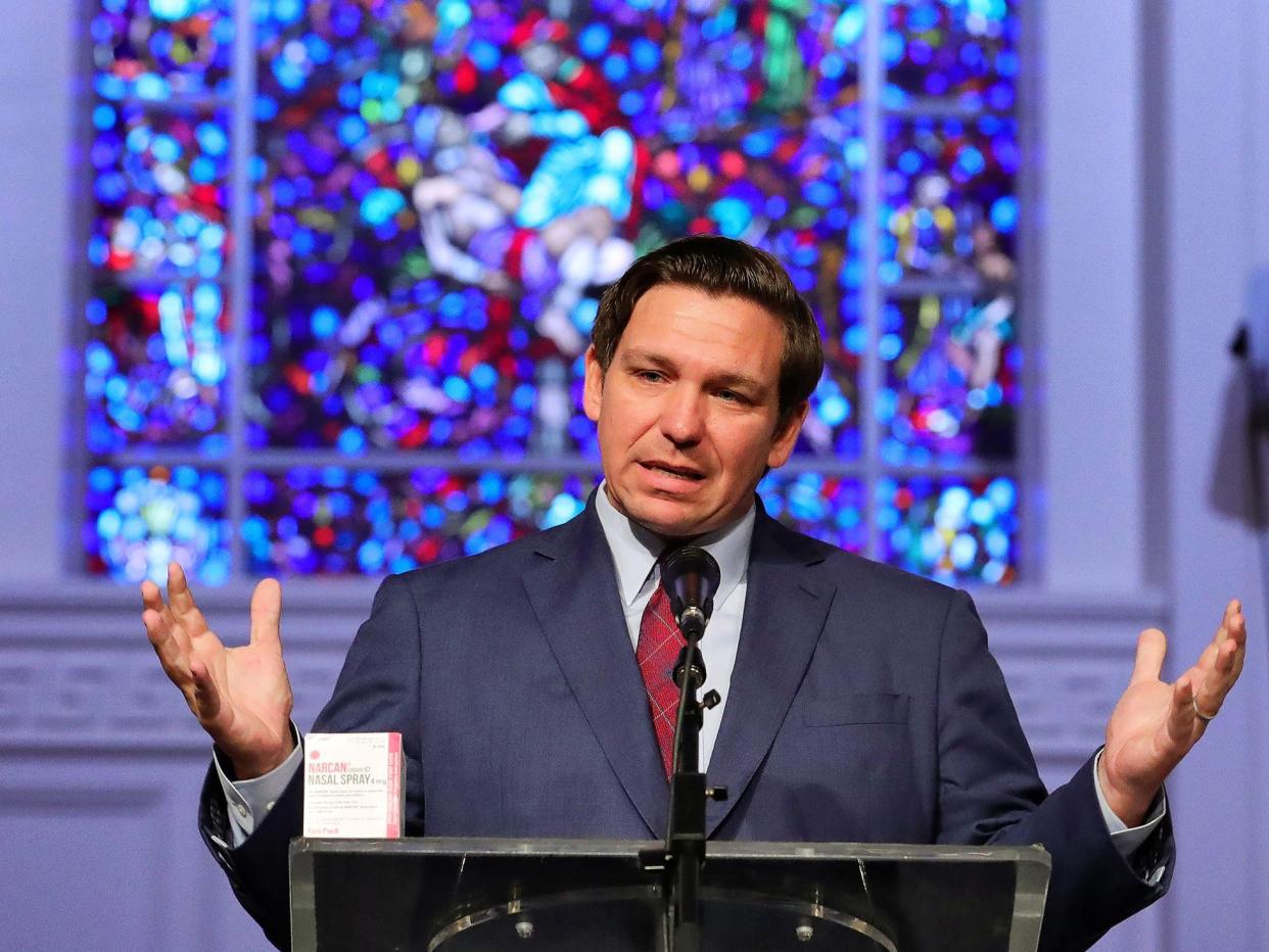 Ron DeSantis at church podium, hands out, with stained glass behind him