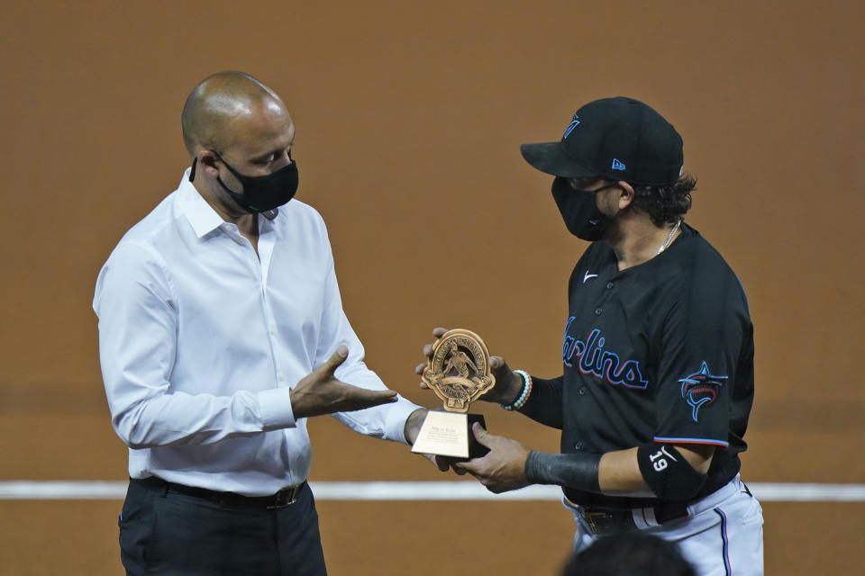 Miami Marlins CEO Derek Jeter, left, presents Miami Marlins shortstop Miguel Rojas a trophy for being chosen as the Marlins' nominee for the Roberto Clemente Award, during a ceremony before the start of a baseball game between the Marlins and the Philadelphia Phillies, Saturday, Sept. 12, 2020, in Miami. (AP Photo/Wilfredo Lee)