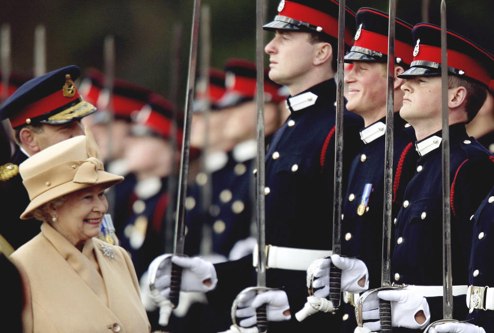 FILE - In this Wednesday, April 12, 2006 file photo, Britain's Prince Harry, second from right, grins and his grandmother Queen Elizabeth II smiles, as she inspects the Sovereign's Parade at the Royal Military Academy in Sandhurst, England. Princess Diana’s little boy, the devil-may-care red-haired prince with the charming smile is about to become a father. The arrival of the first child for Prince Harry and his wife Meghan will complete the transformation of Harry from troubled teen to family man, from source of concern to source of national pride. (Dylan Martinez, Pool Photo via AP, File)